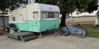 Blue and white airstream trailer with two matching bikes leaned up against it