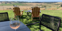 Wine glass on a table in Oregon overlooking a vineyard.