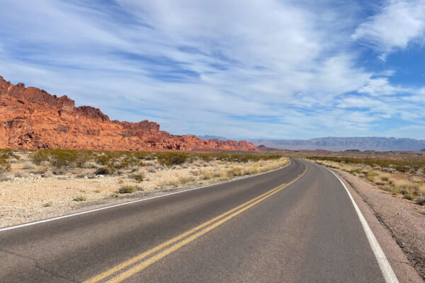 Photo of an open road along the red rocks of Nevada.