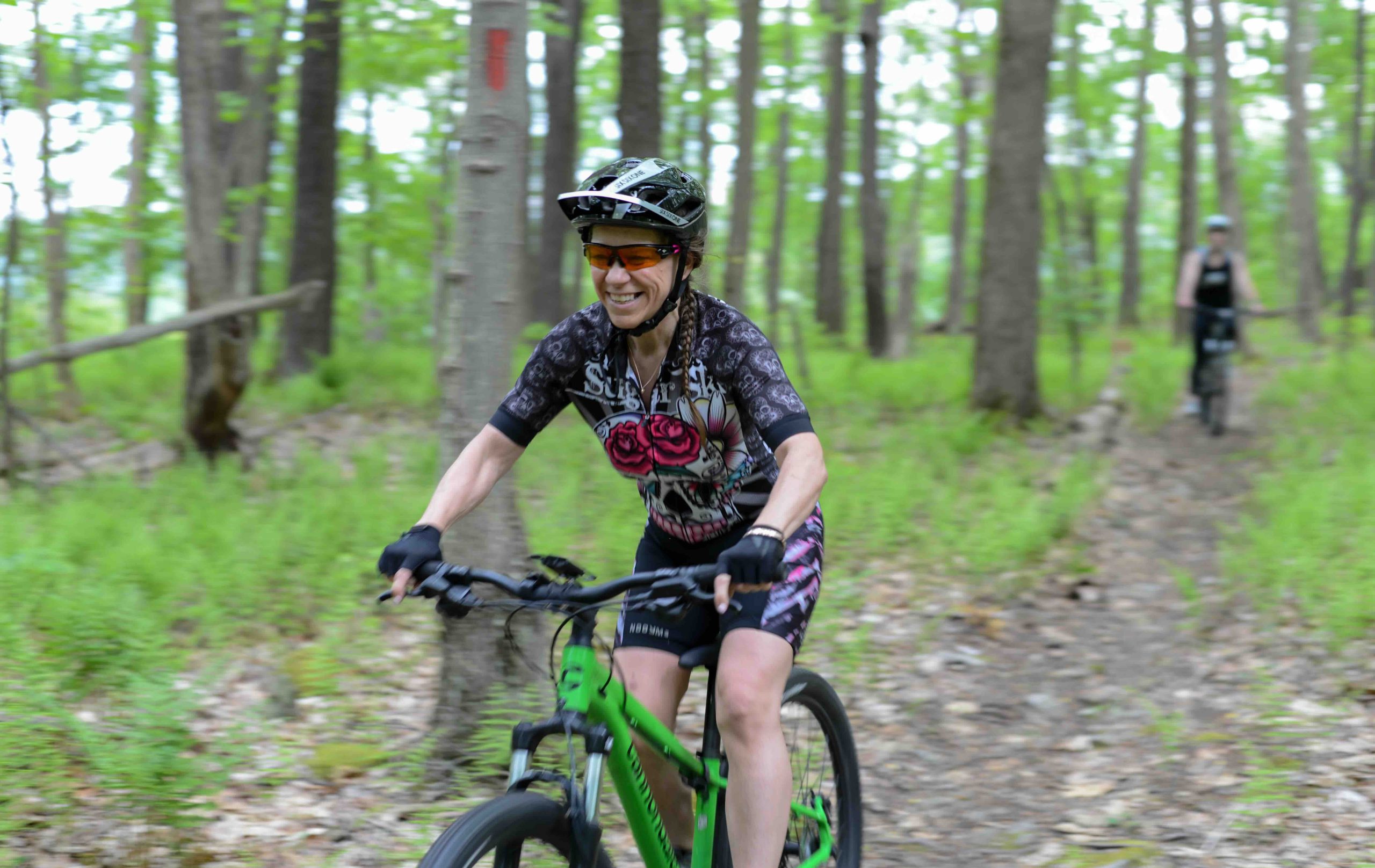 A cyclist happily bikes through the woods.