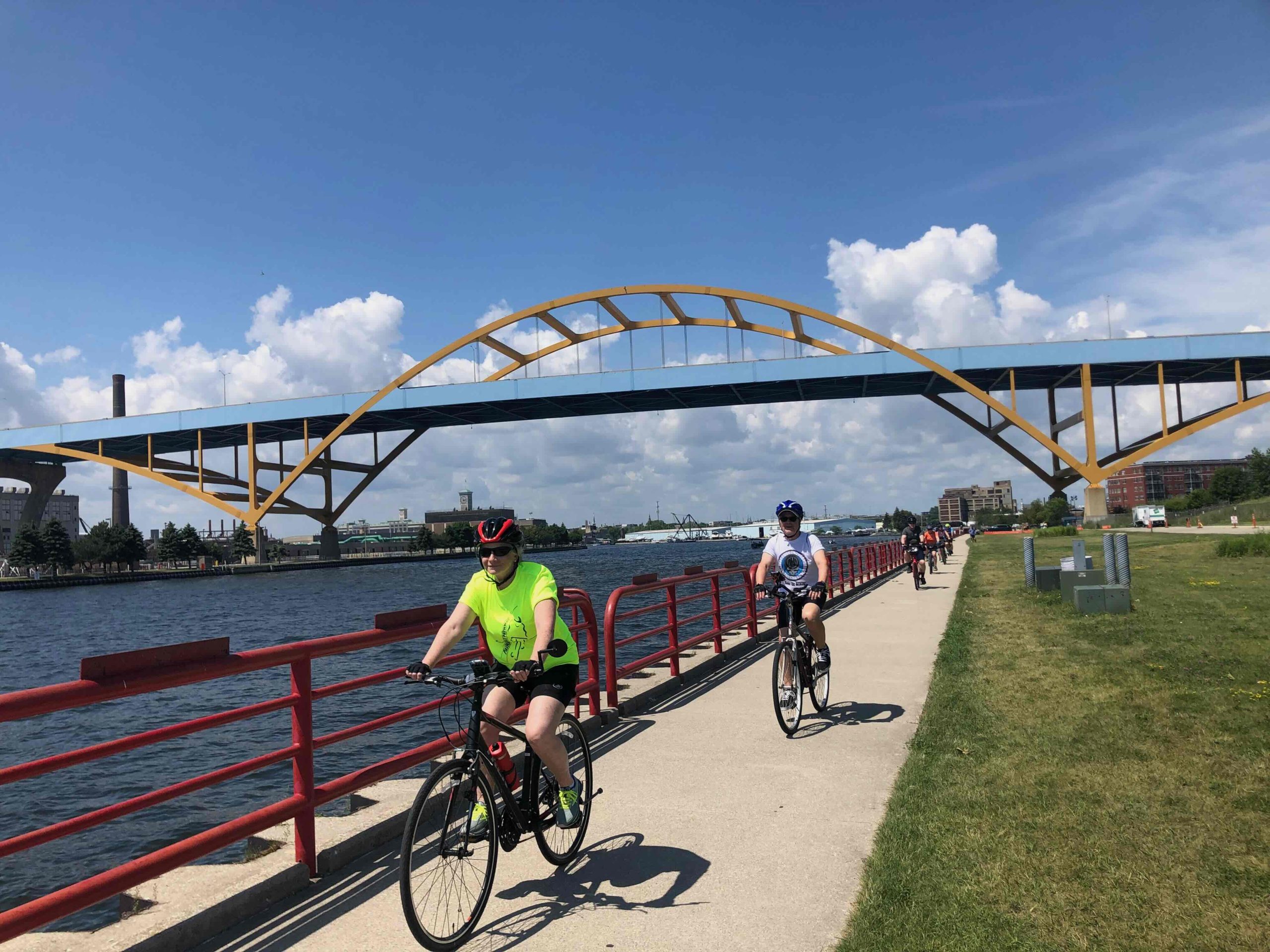 A group of cyclists happily bike next to a river in a city in Wisconsin